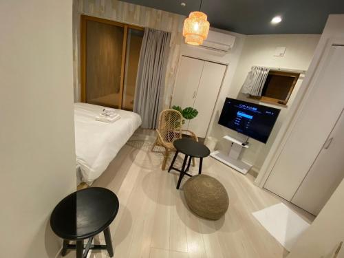 a room with a bed and two tables and a tv at AQA ART 江の島 in Fujisawa