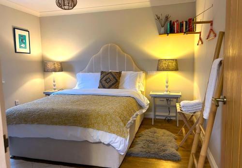 a bedroom with a bed and two tables with lamps at Cargibbitt Annexe in Liskeard