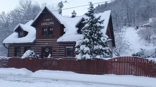 a house covered in snow with a fence in front of it at Chalupa 246 in Vrchlabí
