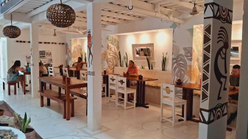 a restaurant with people sitting at tables in a room at Casa Oro Eco Hostel in San Juan del Sur
