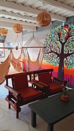 a room with two chairs and a table and a tree mural at Casa Oro Eco Hostel in San Juan del Sur