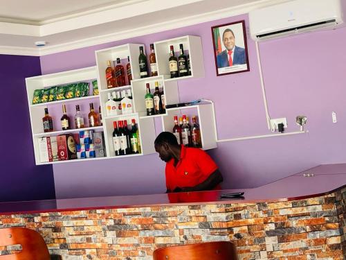 a man sitting at a counter in a bar at Andromeda Executive Lodge in Ndola