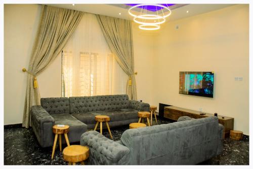 uma sala de estar com sofás e mesas e uma televisão em House 7A em Enugu