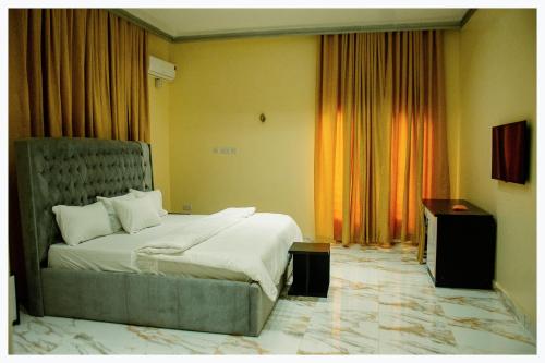 a bedroom with a bed and a dresser and curtains at House 7A in Enugu
