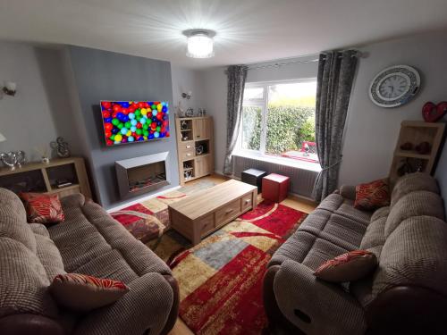 a living room with two couches and a tv at Large private room in Biddulph-Stoke On Trent in Biddulph