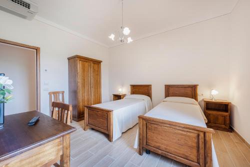 a bedroom with two beds and a table and a desk at Antica Grancia Di Quercecchio in Montalcino