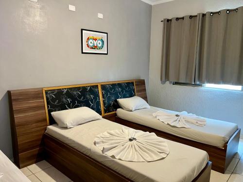 two beds in a small room with a window at Hotel Sunshine in São Bernardo do Campo