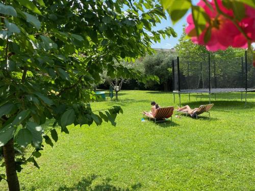 due persone sedute sull'erba di Spazio Friuli - Soreli Apt residenza nel verde a Sevegliano