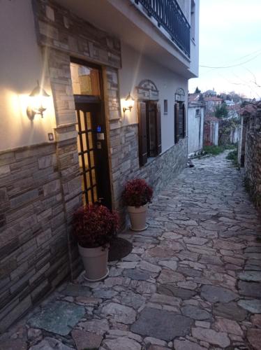 a building with two potted plants on a stone alley at Marousos Central Guesthouse in Portariá