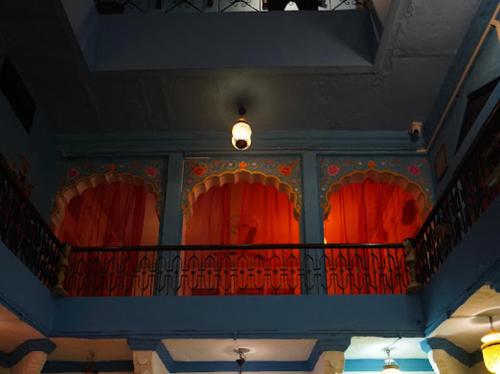 a balcony with red curtains in a building at Yogis Guest House in Jodhpur