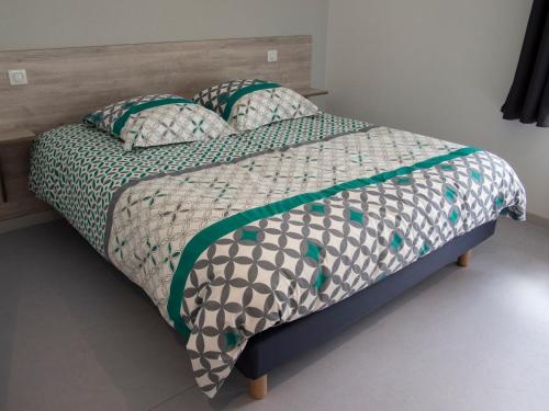 1 cama con edredón y almohadas verdes y blancos en Le Nid des Coucous, en Pulversheim
