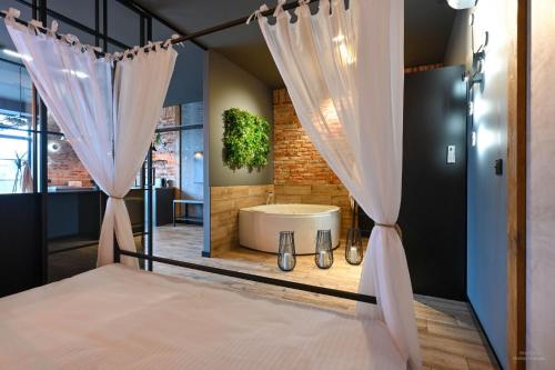 a bathroom with a tub and a bed with curtains at Aparthotel Mamma Mia - Oświęcim in Oświęcim