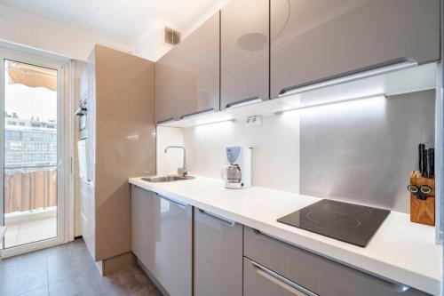 une cuisine avec des armoires blanches, un évier et une fenêtre dans l'établissement Charming 1 bedroom on the top floor, à Cannes