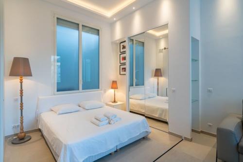 - une chambre blanche avec 2 lits et un miroir dans l'établissement Wonderful one bedroom in Le Gallia, à Cannes