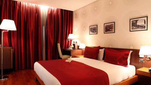 a hotel room with a large bed with red curtains at Tirana International Hotel & Conference Center in Tirana