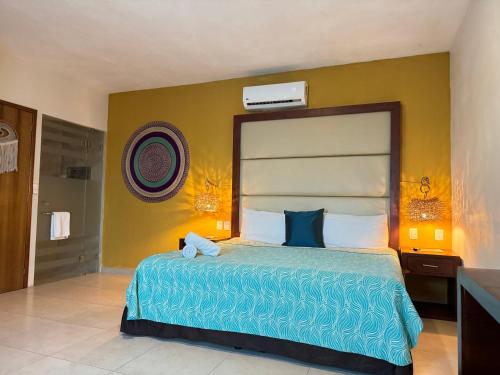 a bedroom with a large bed and a yellow wall at Suites Valentina in Puerto Morelos