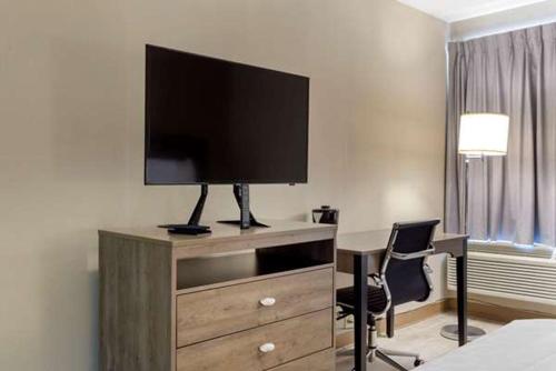 a hotel room with a desk with a television on a dresser at Suburban Studios Raleigh - Crabtree Valley in Raleigh
