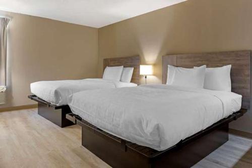 a hotel room with two beds with white pillows at Suburban Studios Raleigh - Crabtree Valley in Raleigh