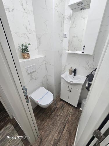 a white bathroom with a toilet and a sink at Apartman Una in Zrenjanin