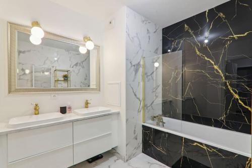 une salle de bain avec deux lavabos et un miroir dans l'établissement Appartement design près Défense, à Bezons