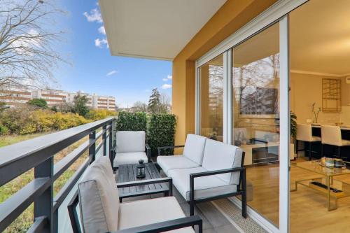 d'un balcon avec des chaises blanches et une table. dans l'établissement Appartement design près Défense, à Bezons