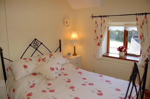 a bedroom with a bed with pink flowers on it at Tre-Allt Gorgeous Cottage in Dolgellau
