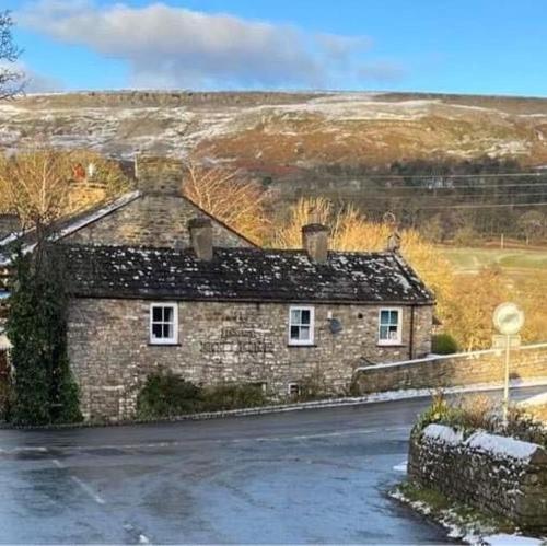 una casa in pietra sul lato di una strada di The Bridge Inn a Reeth