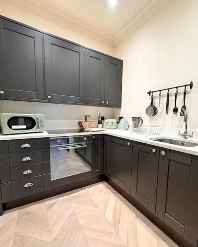 a kitchen with black cabinets and a sink at Luxury Apartment, Old Town - Hastings in Hastings