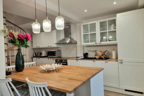 une cuisine avec une table en bois et des armoires blanches dans l'établissement Le Magnolia - Honfleur house - terrace and parking space - 6P, à Honfleur