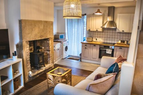 a living room with a couch and a fireplace at Spa Garden Cottage - Upper Hopton in Mirfield