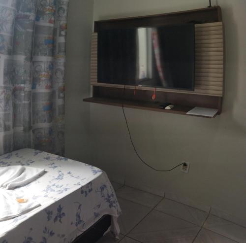 Cette chambre comprend un lit et une télévision murale. dans l'établissement Apartamento Central Privativo, à Boa Vista