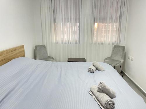 a bedroom with a white bed with towels and two chairs at Tirana AS Apartment 3 City Center in Tirana