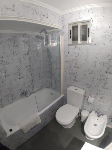 a bathroom with a toilet and a tub and a sink at Torre de laredo 9-3 in Laredo