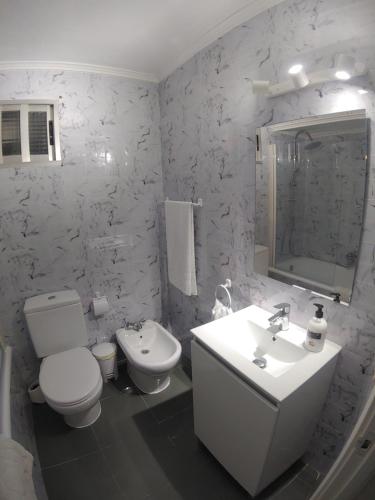 a white bathroom with a toilet and a sink at Torre de laredo 9-3 in Laredo