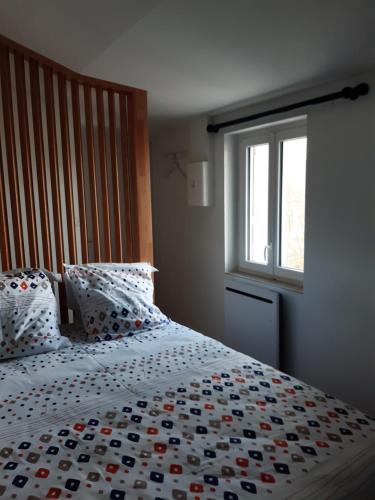 a bedroom with a large bed with a comforter and a window at Niort au bord de l'eau 3 in Niort