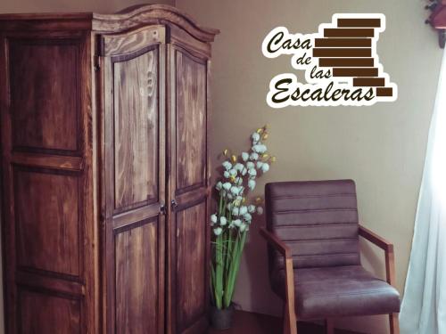 a room with a wooden cabinet and a chair and a staircase at Casa de las Escaleras in Pátzcuaro