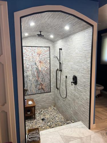 a bathroom with a shower with a painting on the wall at Mermaid's Muse Bed and Breakfast in Brookings