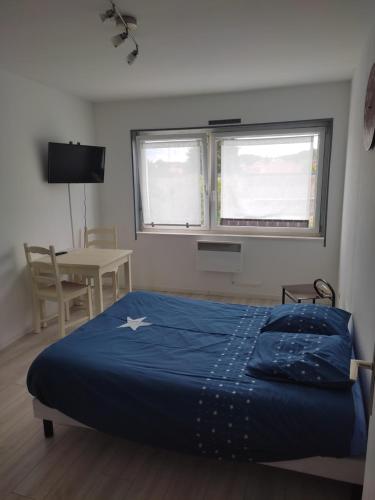 a bedroom with a bed and a table and two windows at gite st nicolas in Freyming