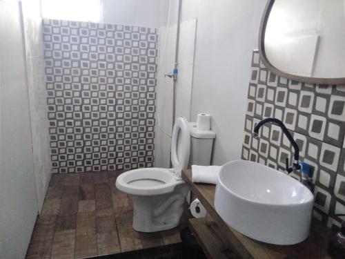 a bathroom with a white toilet and a sink at Studio confortavel - ate 4 pessoas in Araranguá