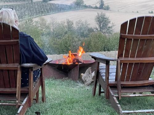 een vrouw in stoelen naast een vuurplaats bij Cascina Vicentini in Alfiano Natta