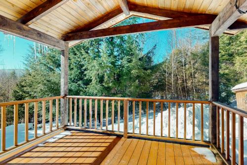 a large wooden deck with a view of the woods at Light-filled Retreat in Mad River Valley 