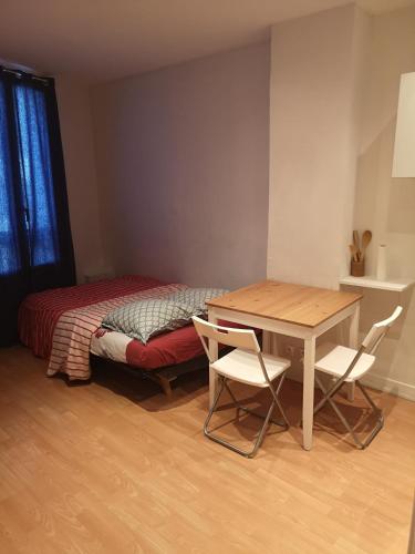 une chambre avec un lit, une table et des chaises dans l'établissement Parfait pour un voyageur solitaire., à Montreuil