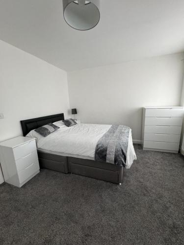 a bedroom with a bed and two white cabinets at Manchester home near City Centre and City stadium in Manchester
