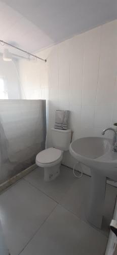a white bathroom with a toilet and a sink at Casa Celeste Búzios in Búzios
