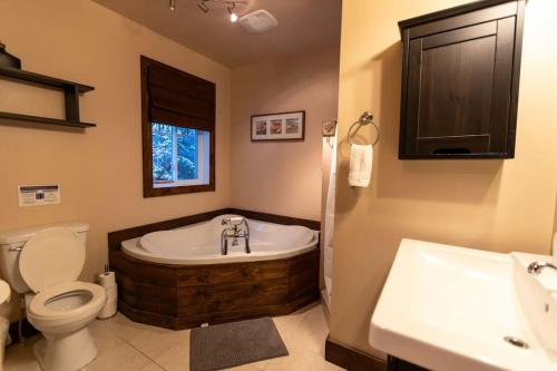 een badkamer met een bad, een toilet en een wastafel bij Royal St-Côme Private Hot Tub Chalet Retreat in Saint Come