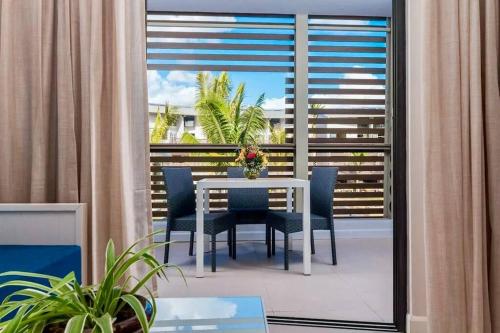 a white table and chairs on a balcony with a window at Cosy studio - Trou-aux-Biches in Trou aux Biches