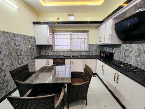 a kitchen with a glass table and some chairs at Motorway Majesty Lodges - Near Islamabad International Airport & Motorway in Islamabad