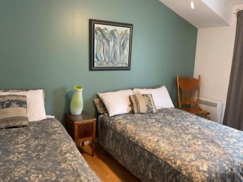 - une chambre avec 2 lits et une photo sur le mur dans l'établissement Gite du Lac Docteur, à Saint-Honoré