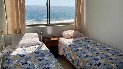 イキケにあるAgua Marina Iqqのベッドルーム1室(ベッド2台付)、海の景色を望む窓が備わります。