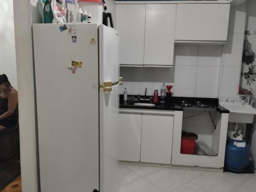 a kitchen with white cabinets and a white refrigerator at Aphostel compartilhado gatinhos perças in Santos